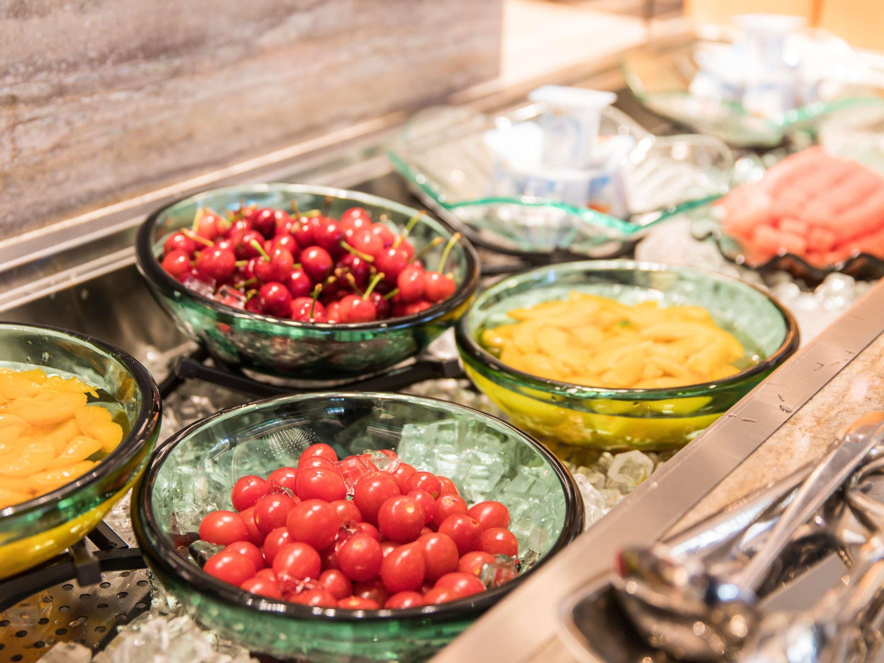 A buffet with various food items including cherries, peaches, and other fruits.