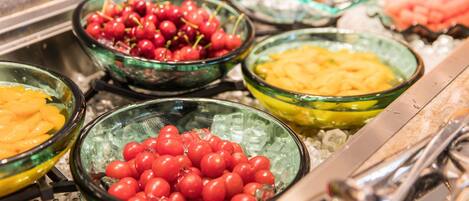 A buffet with various food items including cherries, peaches, and other fruits.