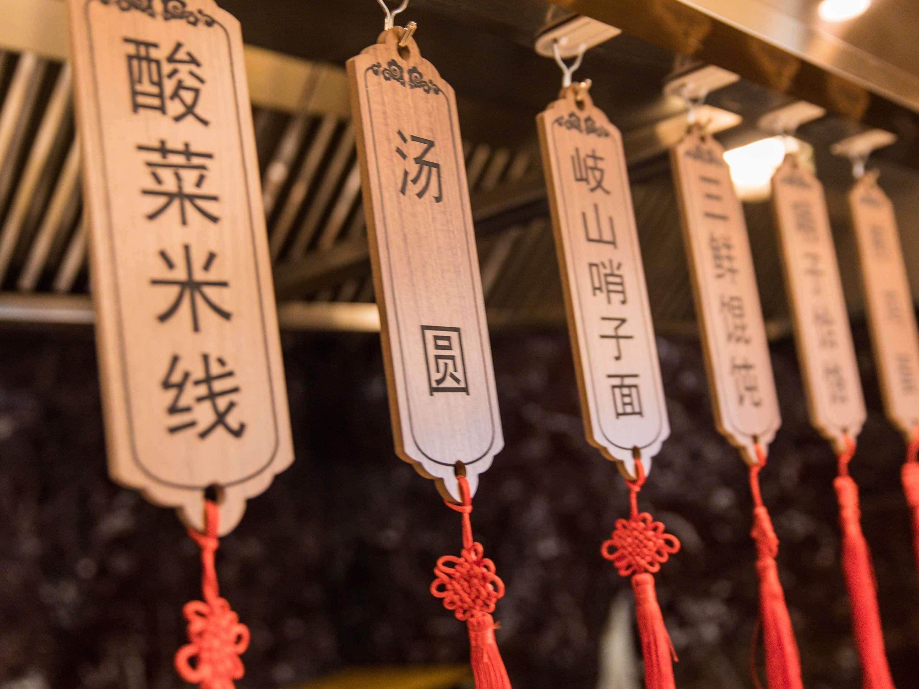 A row of wooden tags with Chinese characters hanging from a ceiling.