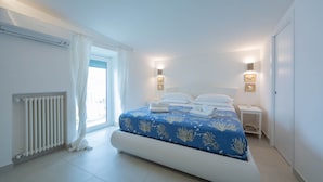 A bedroom with a bed, a radiator, a nightstand, and a wall-mounted light fixture. - "Villa Costanza" with private pool and jacuzzi sea view - Amalfi Coast (-)