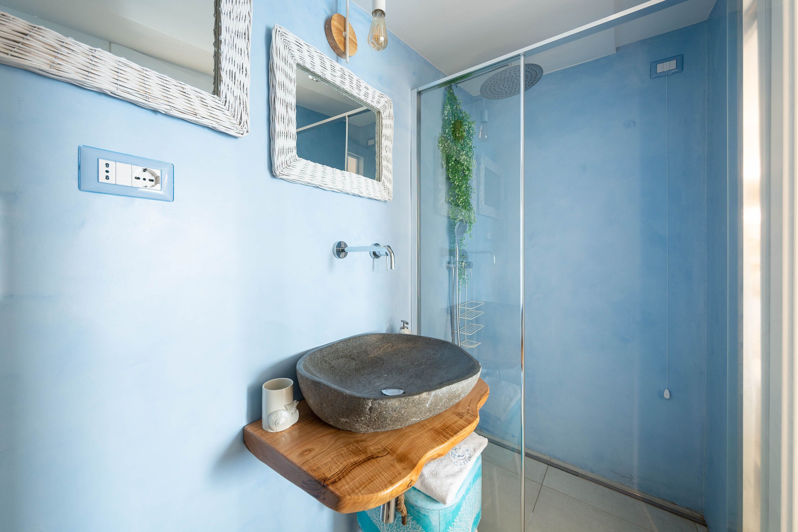 A bathroom with a stone sink, a mirror, and a glass shower enclosure.