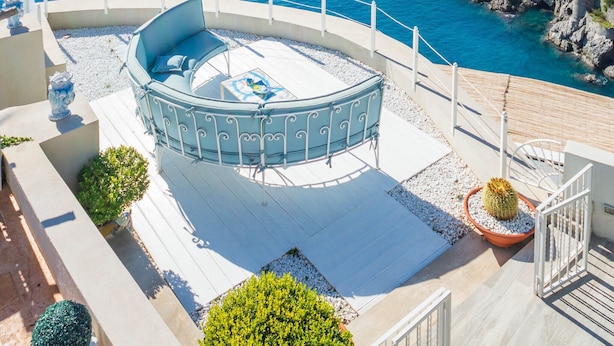 A rooftop terrace with a circular seating area, a view of the sea, and rocky coastline. - "Villa Costanza" with private pool and jacuzzi sea view - Amalfi Coast (-)