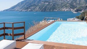 A wooden deck with a pool, white lounge chairs, and a view of the sea and mountains. - "Villa Costanza" with private pool and jacuzzi sea view - Amalfi Coast (-)