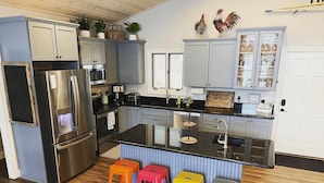 Una cocina moderna con electrodomésticos de acero inoxidable, una isla central y taburetes de colores.