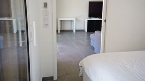 A hotel room with a bed, a TV, a sofa, and a small table. - APARTEMENT CANNES CROISETTE 4th floor (CANNES)