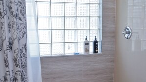 Une salle de bain avec douche, toilettes et fenêtre à carreaux.