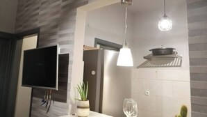 Uma cozinha moderna com geladeira embutida, luminária pendente e uma planta em vaso no balcão.