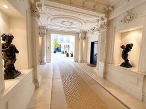 A grand hallway with ornate columns, a patterned floor, and classical statues. - L'appartement Malesherbes (Paris)