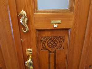 A wooden door with a brass knocker, a nameplate reading "Kranichnest," and a decorative panel.