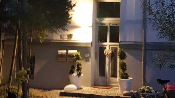 A building with a paved entrance, potted plants, and a bicycle parked outside. - Morizan (Röbel/Müritz)