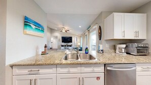 A kitchen with white cabinets, a granite countertop, and stainless steel appliances. - 2nd Floor, Pet Friendly, Close to Marina and Ferry, Golf Cart Access (Port Aransas)