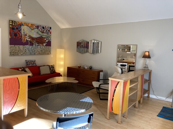 Un salon moderne avec un canapé rouge, une table basse en bois et un coin repas comprenant une table et des chaises en bois.