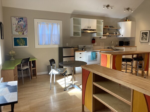 A modern kitchen with a dining area, featuring a round table, chairs, and a bar counter. - Convenient Chic Cottage (Portland)