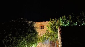 Un sentiero in pietra conduce a un edificio rustico con una piccola finestra e piante in vaso.