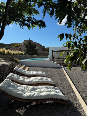 A pool area with stone steps leading to a pool, surrounded by a stone wall and greenery. - Charming Rural House with Pool, 34 km from the Mediterranean (Catí)