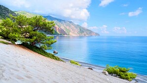 A coastal landscape with a sandy beach, a pine tree, and a calm sea under a clear sky. - Vista Mare Maxima Heated Pool (Georgioupoli)