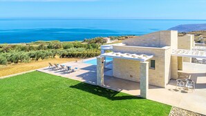 A modern villa with a pool, outdoor seating, and a view of the sea. - Vista Mare Maxima Heated Pool (Georgioupoli)
