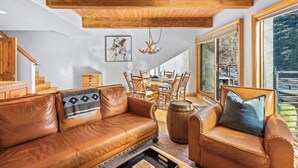 A spacious living room with a leather sofa, a wooden coffee table, and a dining area with chairs and a table.