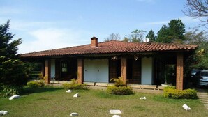 A single-story house with a tiled roof, a covered porch, and a well-maintained lawn with scattered stones. - Beautiful country property surrounded by nature in Jarinú (Jarinu)