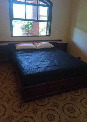 A room with a bed, a window, and a patterned carpet.