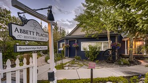 A historic cabin named 'Abbott Placer' with a white picket fence, a large wheel, and hanging flower baskets. - Newly Renovated! Downtown Breck, Private Hot Tub, 5 Fireplaces-Abbett Placer His (Breckenridge)