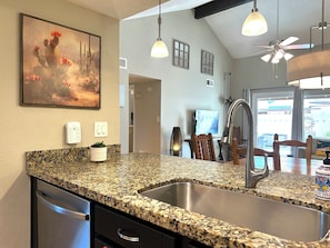 A kitchen with granite countertops, stainless steel appliances, pendant lighting, and a painting on the wall. - Prime Location: Single-Level Gem w/ Garage & Pool! (Chandler)