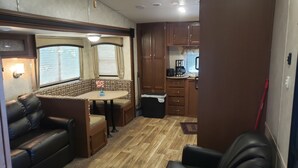 En kompakt autocamper indretning med spiseplads, tekøkken og siddepladser.