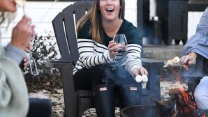 A group of people sitting outdoors near a fire pit, with a building in the background. - *Get-Away by River Trail, Hot Tub, Fire Pit, Bikes, Grill (Kerrville)