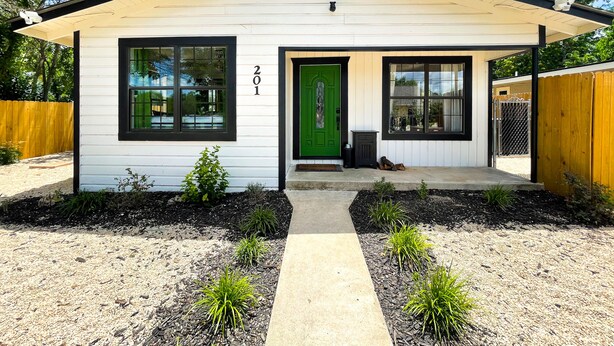 A single-story house with a white exterior, black trim, and a green door. - *Get-Away by River Trail, Hot Tub, Fire Pit, Bikes, Grill (Kerrville)