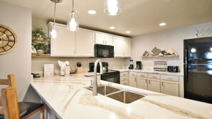 Una cocina moderna con armarios blancos, un refrigerador negro y una encimera de mármol.
