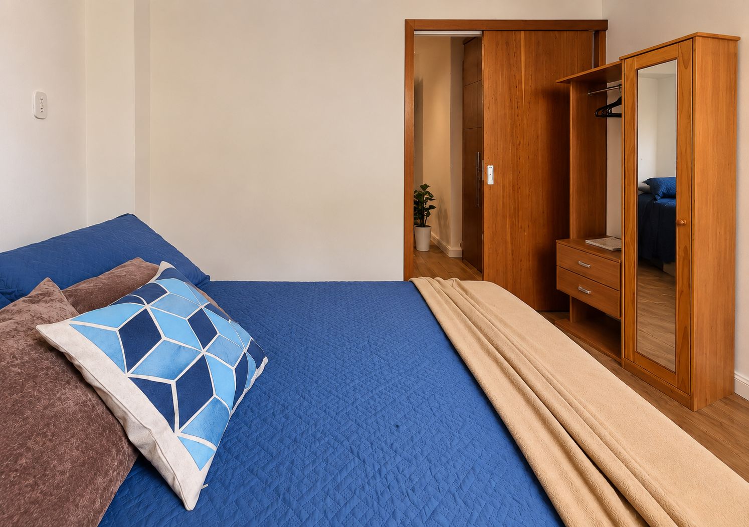 Un dormitorio con cama, armario y espejo.