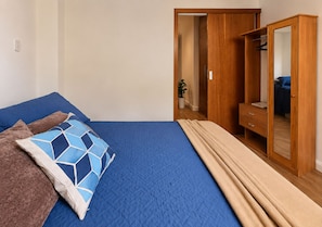 A bedroom with a bed, a wardrobe, and a mirror. - Copacabana: quiet apartment near the beach and metro (RJ)