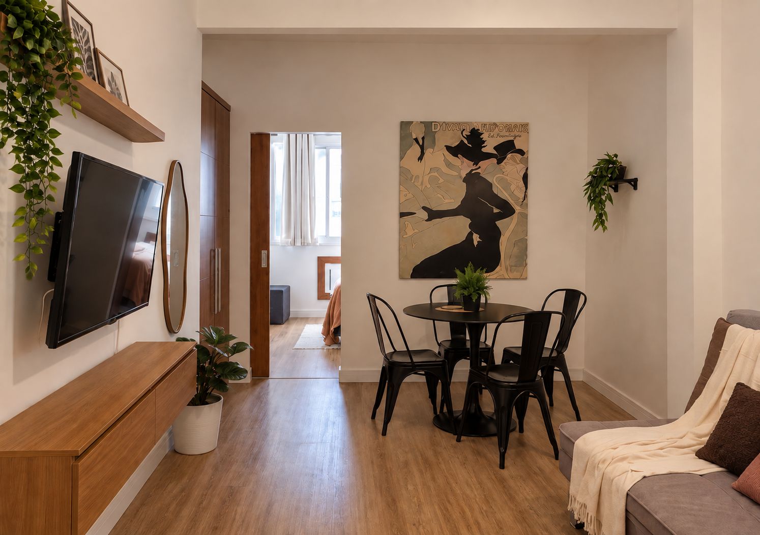 Ein modernes Wohnzimmer mit Flachbildfernseher, einem Essbereich mit rundem Tisch und Stühlen sowie einem großen abstrakten Gemälde an der Wand.