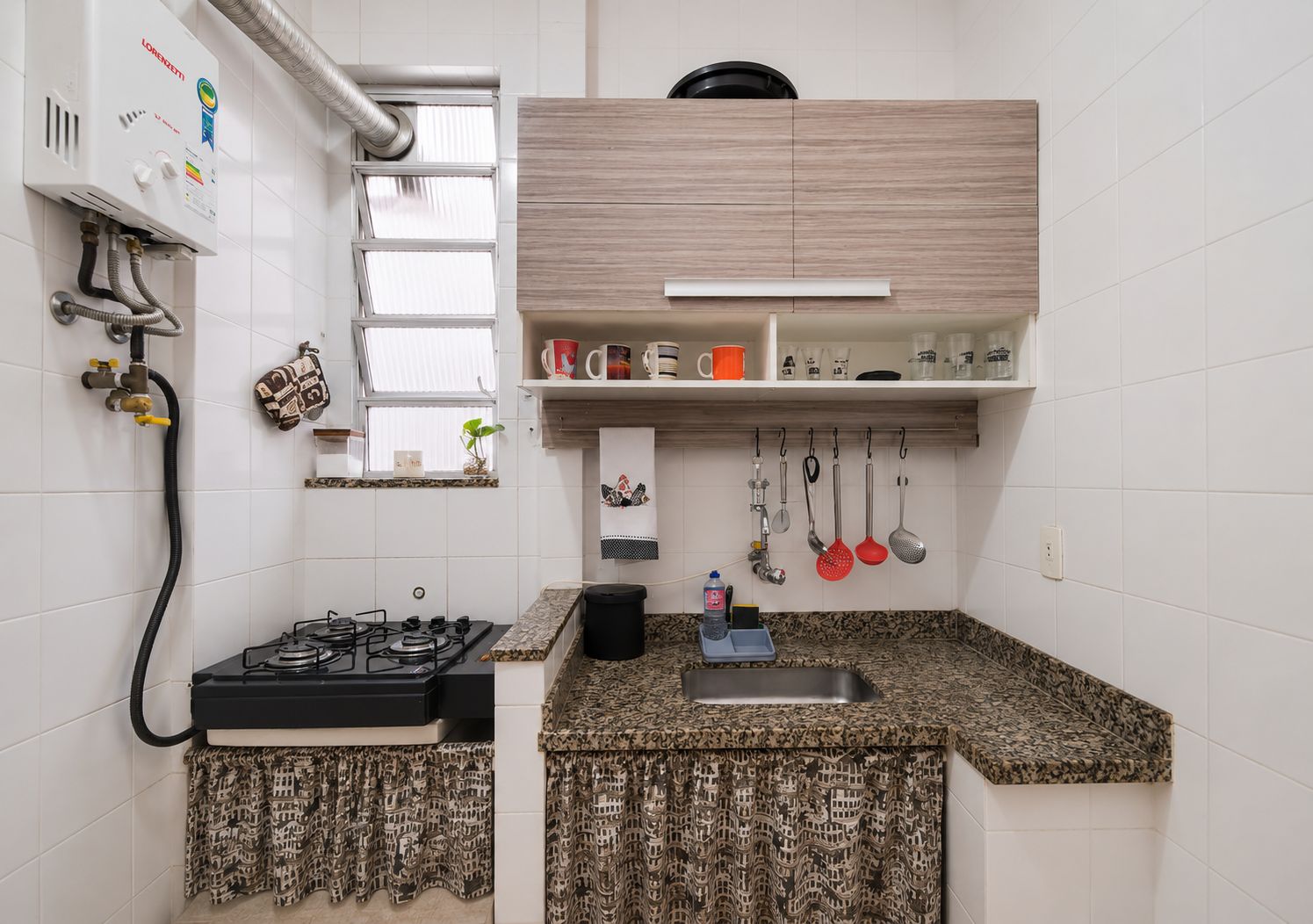 Cocina compacta con estufa a gas, un lavamanos y una ventana con persianas.