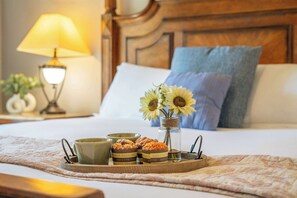 Una cama bien hecha con una bandeja de aperitivos y un jarrón de girasoles.