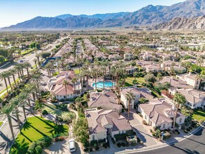 Una zona residencial con casas, palmeras y una piscina.