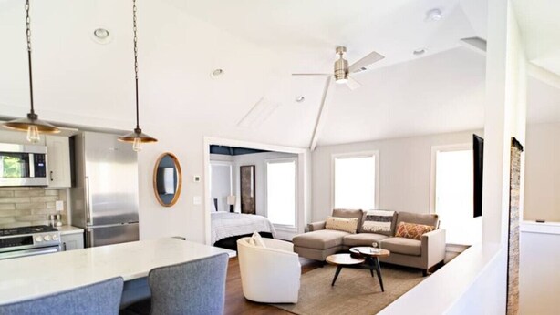 A modern kitchen with a central island, a dining area with two chairs, a sofa, and a coffee table.