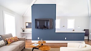 A modern living room with a sofa, a coffee table, and a white armchair. A blue accent wall and a fireplace are visible.