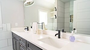 A modern bathroom with a white countertop, black faucet, and a large mirror.
