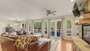 A spacious living room with a leather sofa, a fireplace, and large windows. - Family- Friendly Mountain & Forest View Retreat - 8 guests + kids 5 & under (South Lake Tahoe)