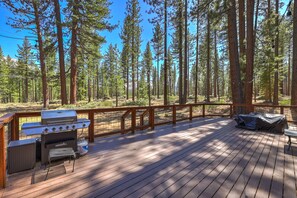 Une terrasse avec un barbecue, une housse de protection pour barbecue et un espace salon.