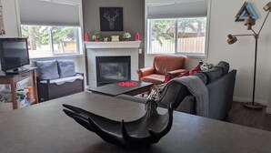A living room with a fireplace, a sofa, a chair, a coffee table, and a television.