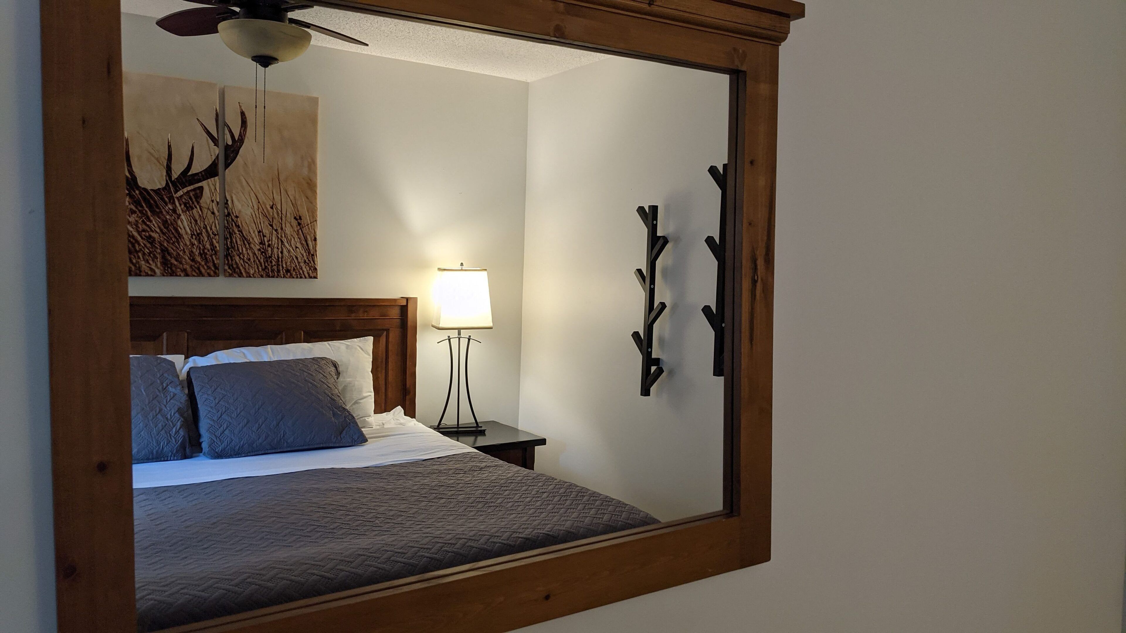 A bedroom with a bed, a nightstand, a lamp, a ceiling fan, and wall art.