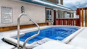 A spa pool area with a wooden fence, a metal pool ladder, and a sign detailing spa rules.