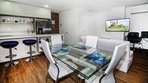 A modern kitchen with white cabinets, a stainless steel refrigerator, and a bar area with blue stools. - ★18th Floor★Coolest building in Medellin★RoofTop Pool/Jacuzzi/Gym★Amazing Views★ (Medellin)