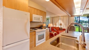 A compact kitchen with a refrigerator, microwave, stove, and sink.
