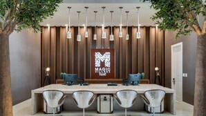 Un área de recepción con una larga barra, cuatro sillas y un cartel que dice "MAGIC VILLAGE RESORT".