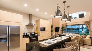 Una cocina moderna con una isla central, electrodomésticos de acero inoxidable y un comedor con sofá y sillas.
