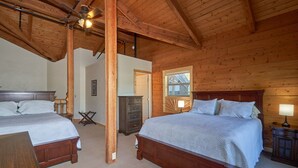 Ein Schlafzimmer einer Holzhütte mit zwei Betten, einem Deckenventilator und einem Fenster.