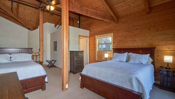 Une chambre dans une cabane en bois, avec deux lits, un ventilateur de plafond et une fenêtre.